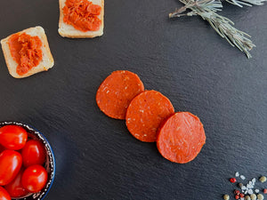 Tranches de Nduja halal épicée sur planche avec herbes