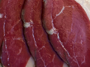 Gros plan sur des tranches de magret de canard halal fumé au bois de hêtre, à la chair rouge foncé bordée d'une fine couche de gras
