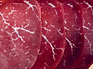 Gros plan de tranches fines de noix de bœuf séchée halal montrant le persillage naturel de la viande
